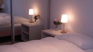 Et hotelværelse med en stor seng, to sengeborde med lamper og et spejl på væggen.