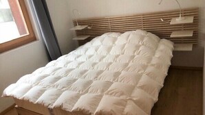 Un letto con un materasso bianco trapuntato, una testiera in legno e lampade ai comodini.