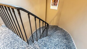 A staircase with a black metal railing and a patterned carpet. - Le White by Sweett (Paris)
