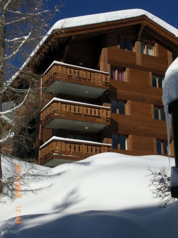 Un edificio de madera de varios pisos con balcones, rodeado de nieve.