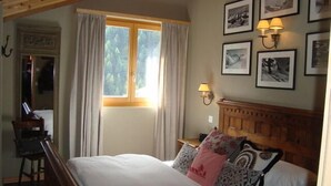 Un dormitorio con una cama de madera, una mesita de noche, una lámpara y cuadros en la pared.