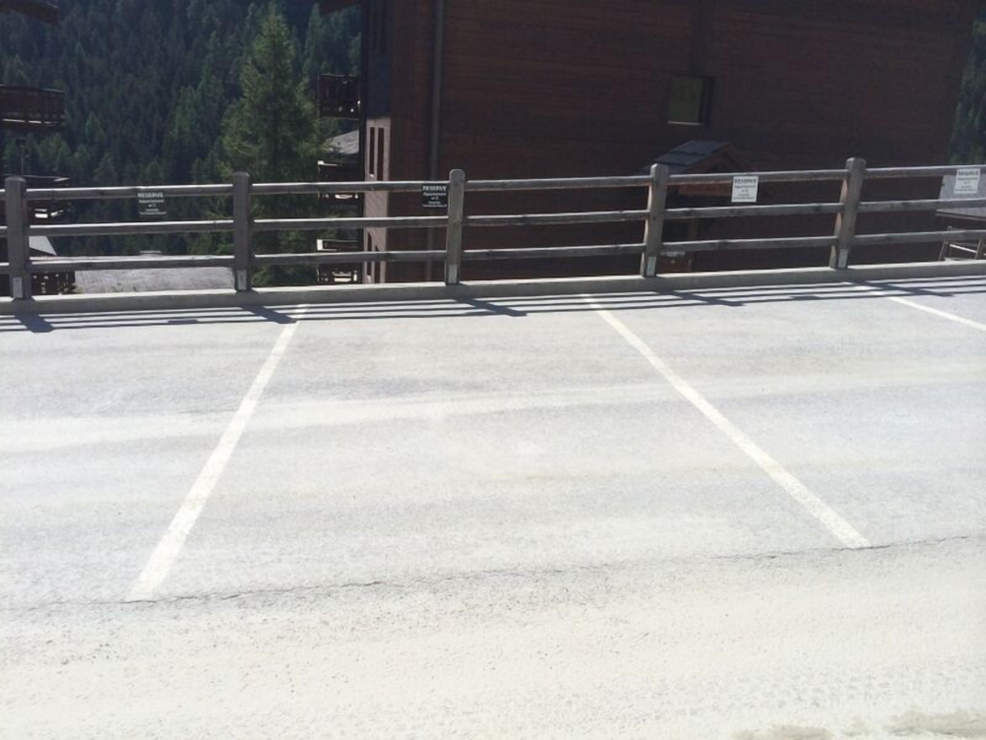 A parking area with marked spaces, a wooden fence, and a building with a sign that reads "RESORT".