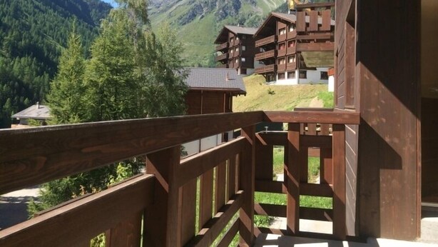 Un balcone in legno con vista su una montagna e una foresta.