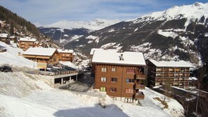Un villaggio montano innevato con edifici in legno e una seggiovia.