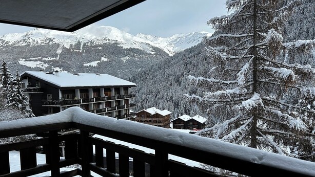 Ein Balkon mit Blick auf verschneite Berge und eine Berghütte.