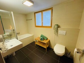 Ein Badezimmer mit Badewanne, Waschbecken, Toilette und Fenster.