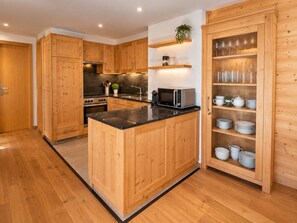 A modern kitchen with wooden cabinets, a central island, and built-in shelves for glassware. - Modern 4-room duplex for 7 to 8 people 2 minutes from the ski lifts: 1 bedroom with double bed and b (Grimentz)