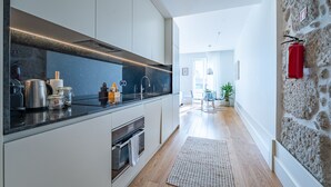 Een moderne keuken met een donker aanrecht, roestvrijstalen apparatuur en een stenen wand.