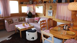 Un interior acogedor de cabaña con un sofá a rayas, una mesa de comedor de madera y un tapete de cuero de vaca.