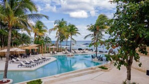 A pool area with lounge chairs, palm trees, and a view of the ocean. - The Beachfront by The Fives Hotels Á la Carte - Adults Only (Playa del Carmen)