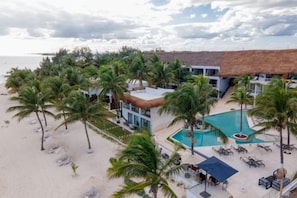 Un complejo turístico con piscina, palmeras y acceso a la playa.