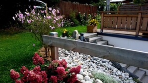 Un jardín con un banco de madera, un jardín de rocas y diversas plantas en flor.