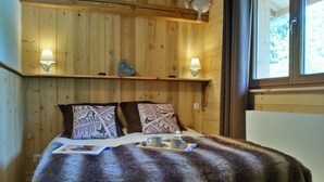 Una habitación con paneles de madera, una cama, dos lámparas de pared y un ventanal.