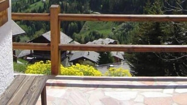 A wooden balcony with a view of a mountainous landscape, including snow-capped peaks and a valley with greenery. - Comfortable chalet for 5 persons : Living room with fireplace - kitchen with dishwasher, microwave a (Grimentz)