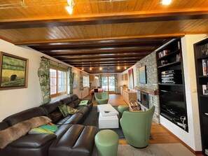 Uma sala de estar aconchegante com um sofá de couro, poltronas verdes e uma lareira.