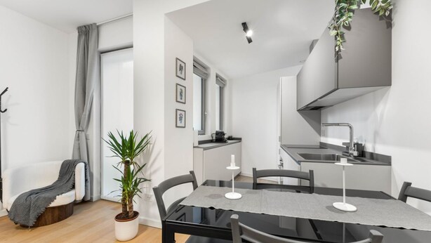 A modern kitchen with a built-in stove, a dining area with a table and chairs, and a potted plant. - VivimiHome - Navigli Design Loft con Terrazzo (Milano)
