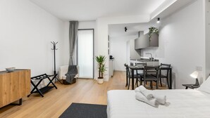A modern, well-lit bedroom with a large bed, a desk, and a dining area. - VivimiHome - Navigli Design Loft con Terrazzo (Milano)