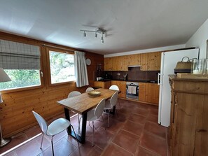 Eine Küche mit Holzausstattung, einem Esstisch mit Stühlen, einem Herd und einem Kühlschrank.
