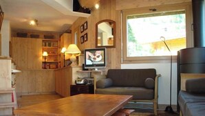 Ein gemütliches Wohnzimmer mit einem Holzesstisch, einer Couch und einem Fernseher.
