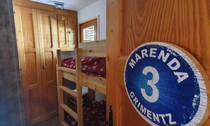 A room with a bunk bed, a wooden wardrobe, and a circular sign with the name 'MARENDA' and the number '3'. - Comfortable 4 room apartment for 4-6 persons in the old village : Living room  - kitchen with dishwa (Grimentz)