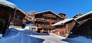 A wooden lodge with multiple balconies and a red vehicle parked in front. - Comfortable 4 room apartment for 4-6 persons in the old village : Living room  - kitchen with dishwa (Grimentz)
