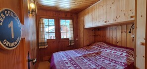En stuga med träpanel, ett rum med en säng, ett fönster med gardiner och en skylt på väggen.
