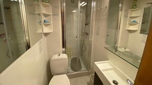 Ein Badezimmer mit Duschkabine, Toilette und Waschbecken mit Spiegel.