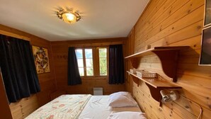 Ein Zimmer in einer Holzhütte mit einem Bett, einem Regal mit Gegenständen und einem Bild an der Wand.
