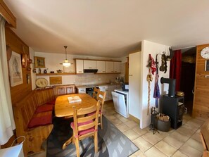 Eine gemütliche Küche mit Holzausbau, einem Esstisch mit Stühlen, einem Einbauofen und einem Holzofen.