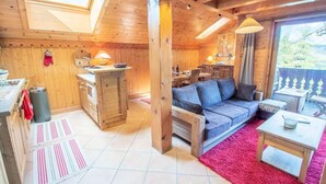 Ein gemütliches Blockhaus-Interieur mit Küche, Essbereich und Wohnzimmer, inklusive Sofa und kleinem Tisch.
