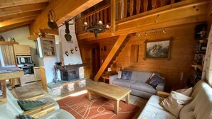 Interior acogedor de una cabaña de madera con sala de estar, cocina y comedor.