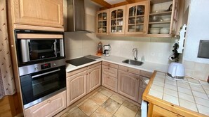 Una cocina con armarios de madera, un horno de acero inoxidable, un microondas, un lavamanos y una encimera.