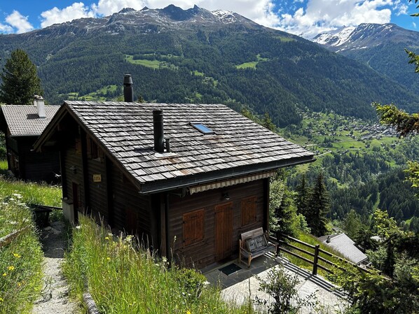 A rustic wooden cabin with a sloped roof, a chimney, and a bench outside. - Very comfortable chalet for 6 persons: ground floor: living room with chimney - kitchen with dishwas (Grimentz)