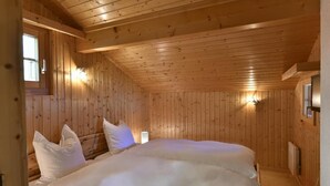 Een kamer met houten lambrisering, een bed, een raam en wandlampen.