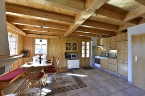 Ein Holzblockbau-Innenraum mit Essbereich, Küche und einem großen Fenster.