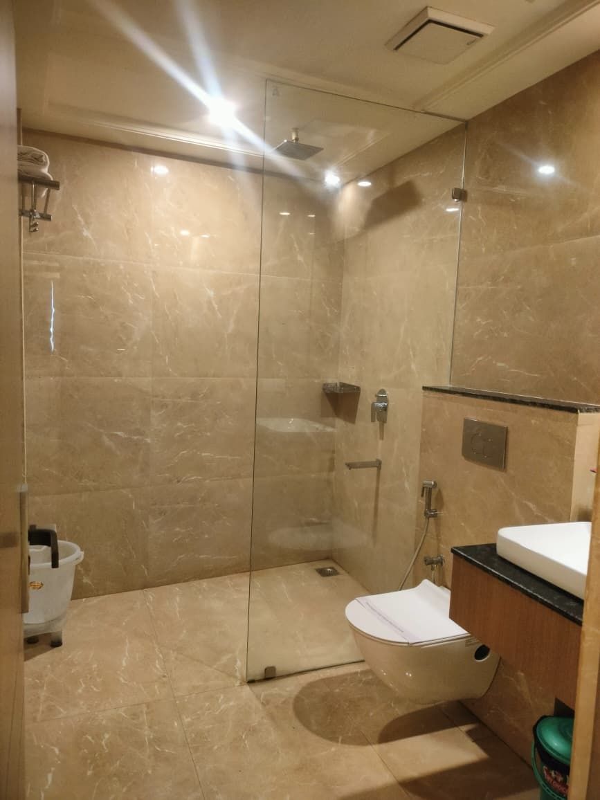 Un baño moderno con ducha envuelta en vidrio, inodoro y lavabo con encimera de madera.