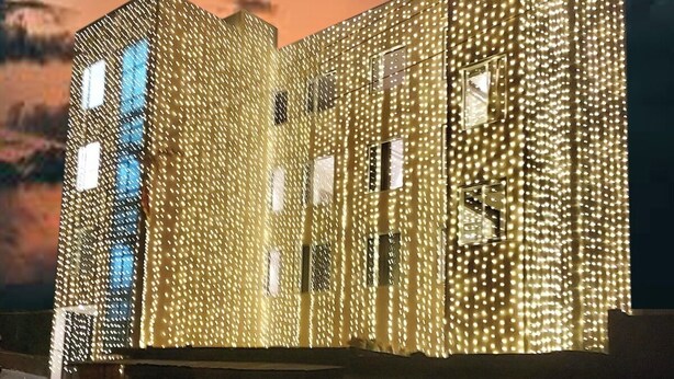 A building with a unique facade covered in lights, large windows, and a flat roof.