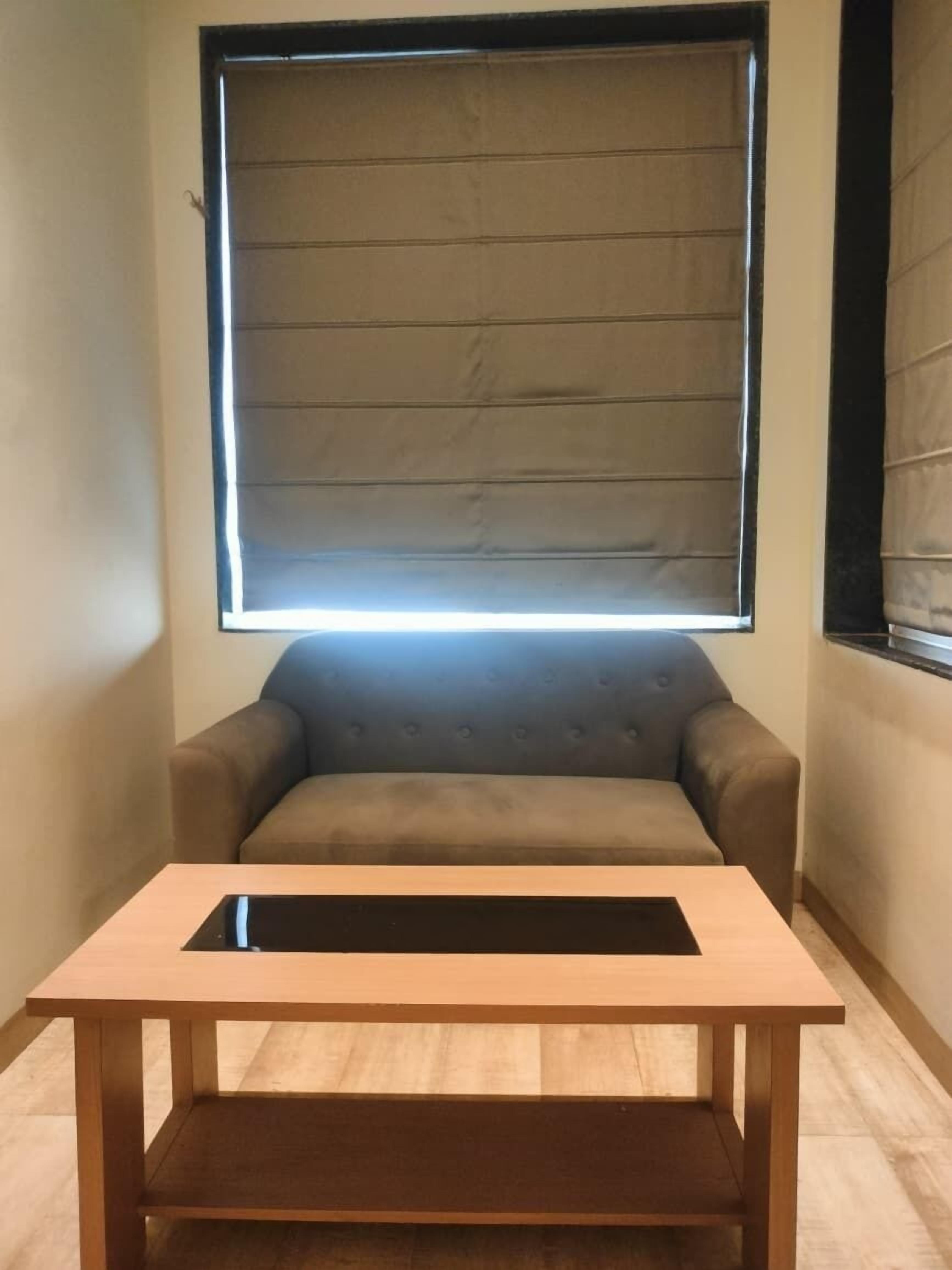 Una habitació amb un sofà, una taula de fusta i una finestra amb persianes.