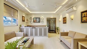A modern living room with a reception desk, two sofas, a coffee table, and a dining area.