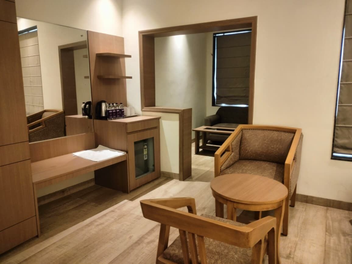 Una habitación compacta con un escritorio de madera, una mesita redonda pequeña y un sofá.