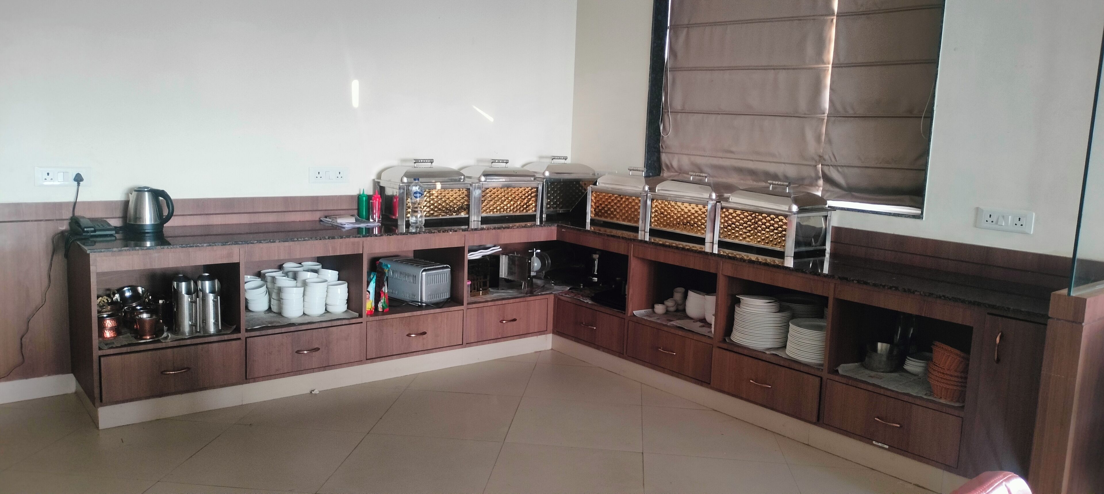Una cocina con armarios de madera, electrodomésticos de acero inoxidable y una ventana con persiana.