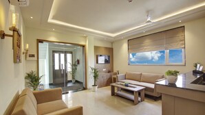 A modern living room with a sofa, coffee table, and a kitchen area with a TV.