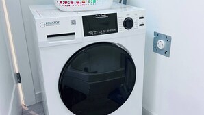 En tvättmaskin med frontmatning, en kontrollpanel, en korg på ovansidan och ett eluttag i närheten.