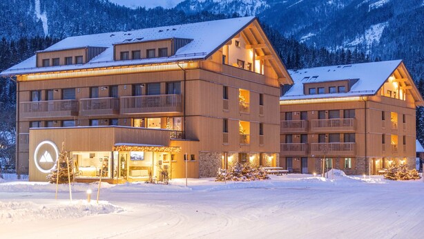 A multi-story hotel with balconies, a ski lift, and a snowy mountain backdrop. - Dormio Aparthotel Hinterstoder (Hinterstoder)