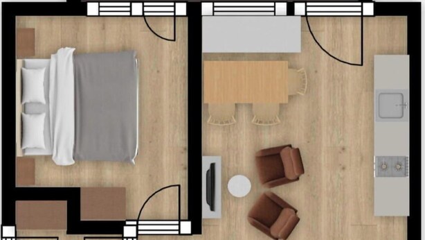Ein Hotelzimmer mit Bett, Sitzgelegenheit, Küchenzeile und Bad.