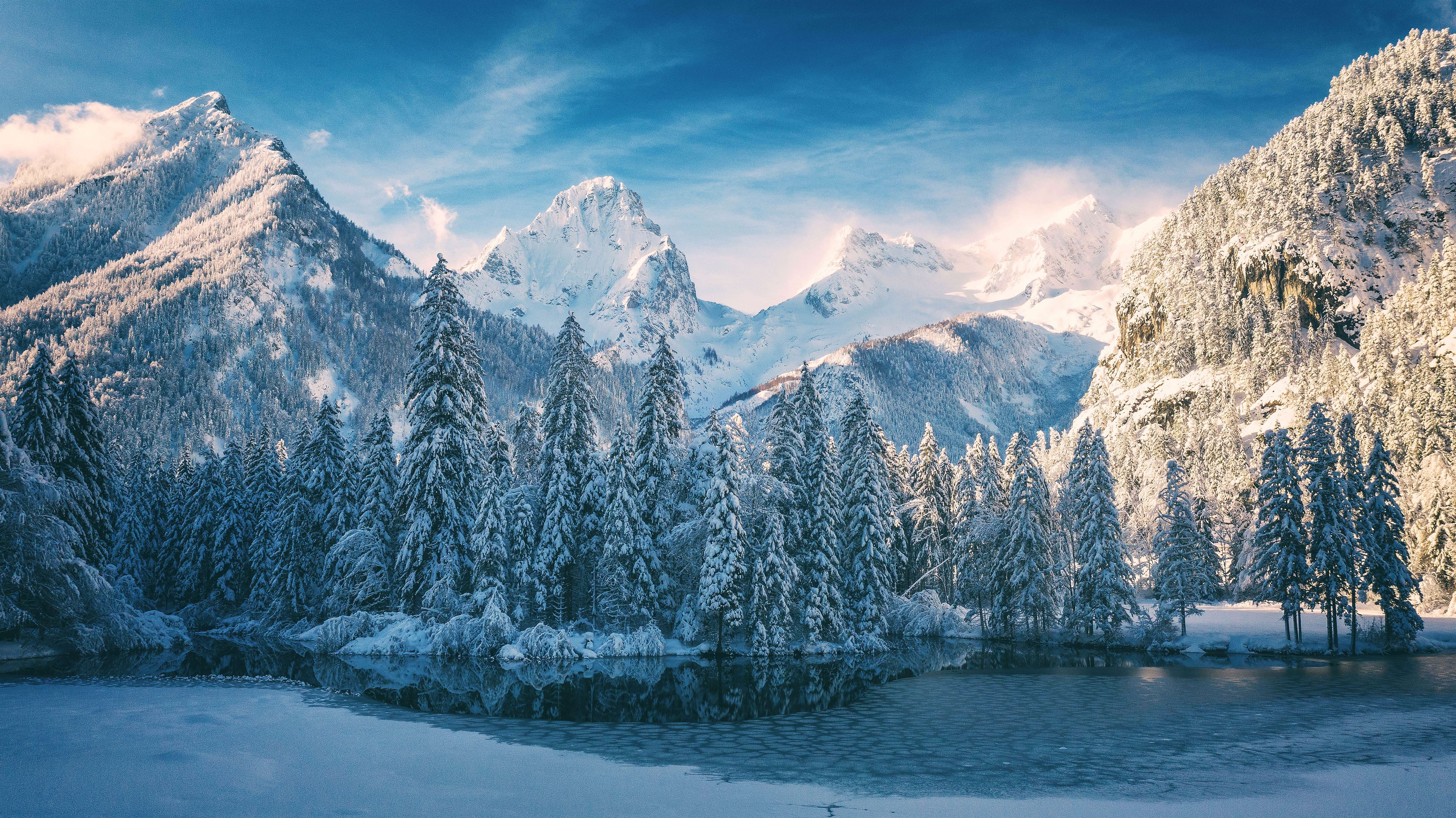 A mountainous landscape with snow-covered trees and a frozen lake.