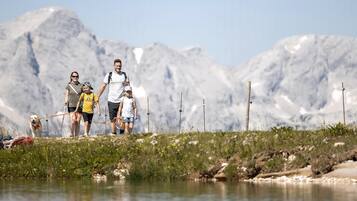 A family with a dog near a body of water with mountains in the background.