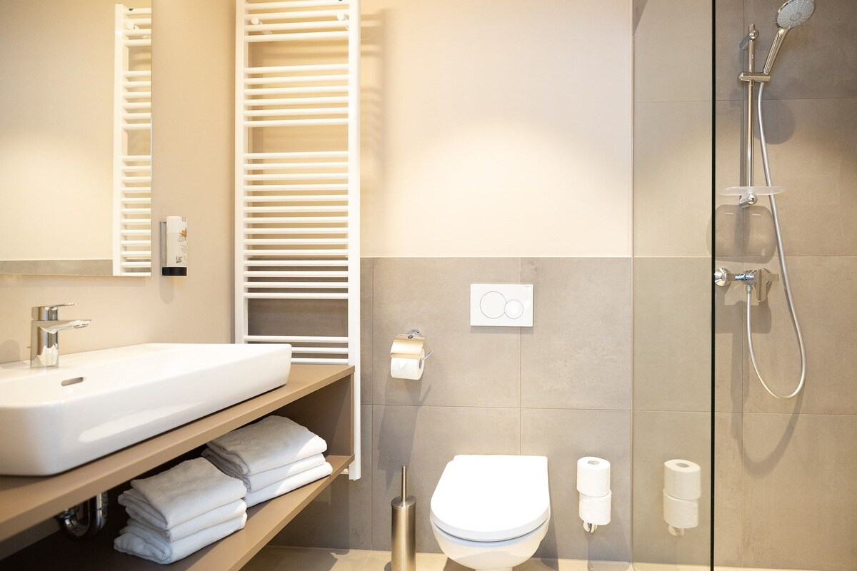 A modern bathroom with a sink, toilet, and shower.