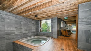 Ein modernes Badezimmer mit Holzboden, grauen Steinwänden und einer Holzbalkendecke.