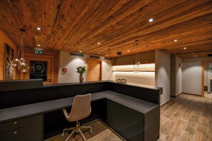 A reception area with a wooden ceiling, a reception desk, a white office chair, and a plant. - Brand new with spa : comfortable 4 room apartment for 6-7 people on the lower floor in front of the (Grimentz)